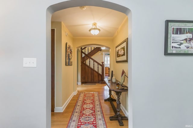 corridor featuring light wood-type flooring and ornamental molding