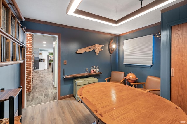 dining area featuring a tray ceiling, crown molding, and light hardwood / wood-style floors