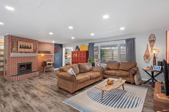 living room with wood-type flooring and a brick fireplace