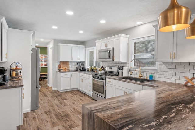 kitchen featuring backsplash, stainless steel appliances, sink, light hardwood / wood-style flooring, and white cabinetry