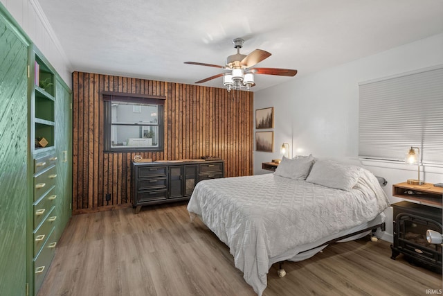 bedroom featuring light wood-type flooring, ceiling fan, and wood walls