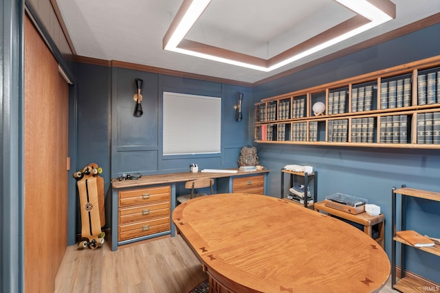 home office featuring light wood-type flooring, a tray ceiling, and crown molding