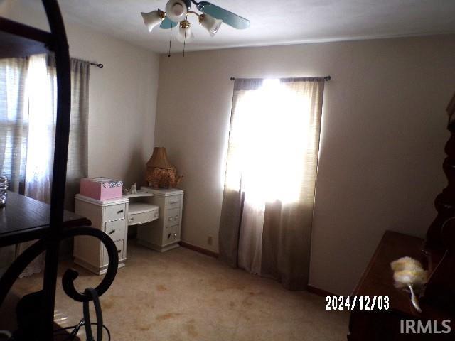 carpeted home office with ceiling fan