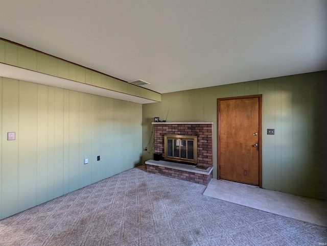 unfurnished living room featuring a fireplace, light carpet, and wood walls