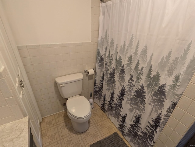 bathroom with curtained shower, tile walls, and toilet