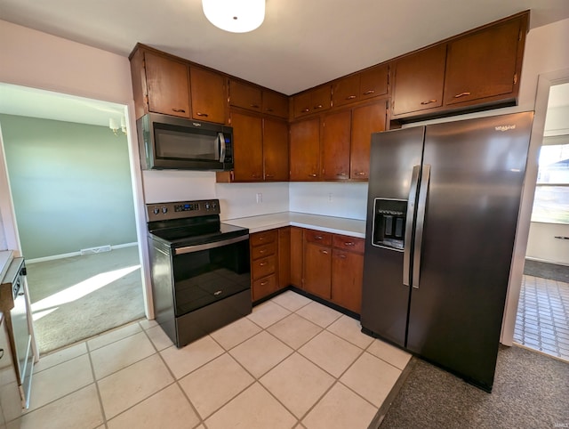 kitchen with light tile patterned flooring and black appliances