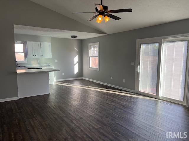 unfurnished living room with ceiling fan, dark wood-type flooring, and vaulted ceiling