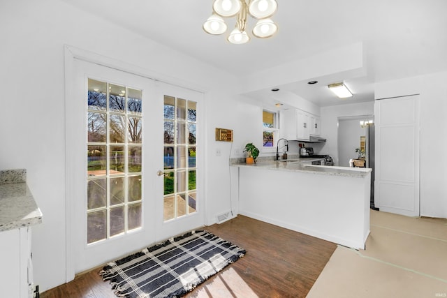 kitchen featuring white cabinets, dark hardwood / wood-style floors, a wealth of natural light, and a notable chandelier