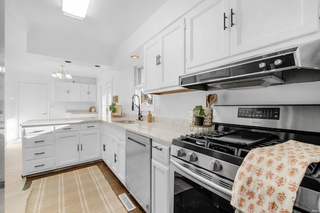 kitchen featuring light stone counters, stainless steel appliances, sink, white cabinets, and a chandelier