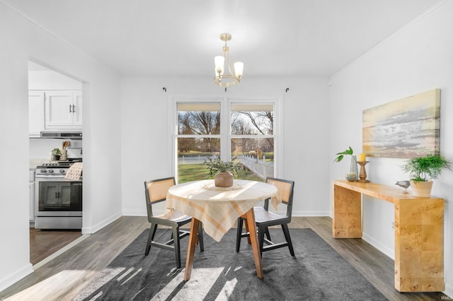 dining area featuring dark hardwood / wood-style floors, ornamental molding, and a notable chandelier