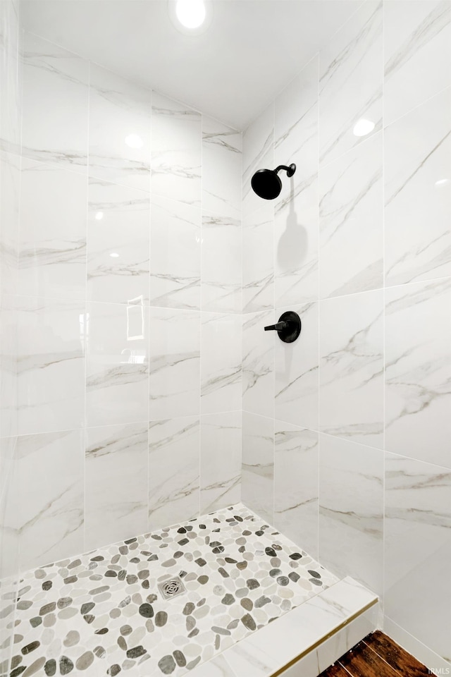 bathroom with a tile shower and wood-type flooring