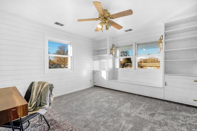 unfurnished office featuring carpet flooring, ceiling fan, and wooden walls