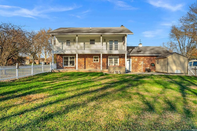 back of house with a lawn, a storage unit, and a balcony