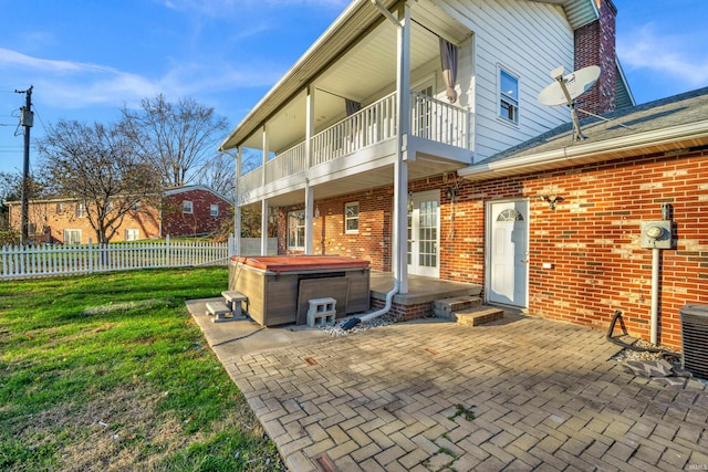 back of house featuring a yard, a patio area, a balcony, and a hot tub