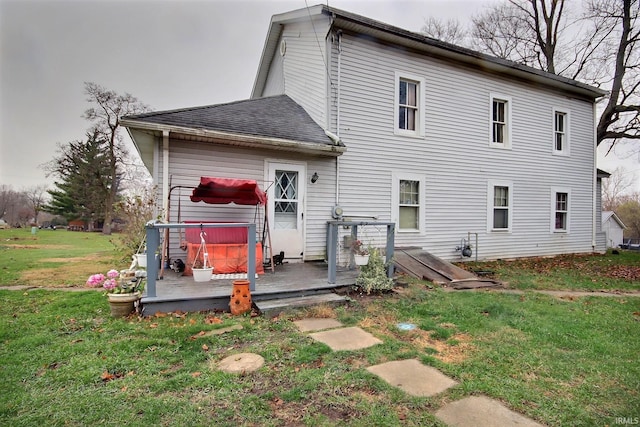 rear view of house featuring a wooden deck, a yard, and a hot tub