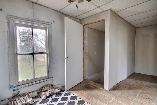 interior space with tile patterned floors, a drop ceiling, and ceiling fan