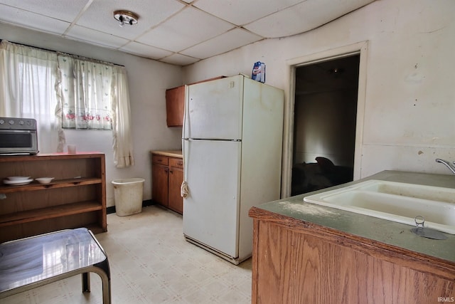 kitchen featuring sink, a drop ceiling, and white refrigerator