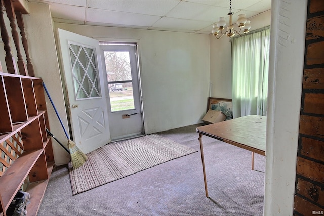 entryway with a chandelier, a paneled ceiling, and carpet flooring