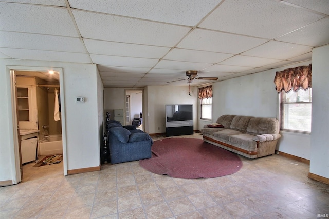 living room featuring a paneled ceiling, ceiling fan, and a healthy amount of sunlight