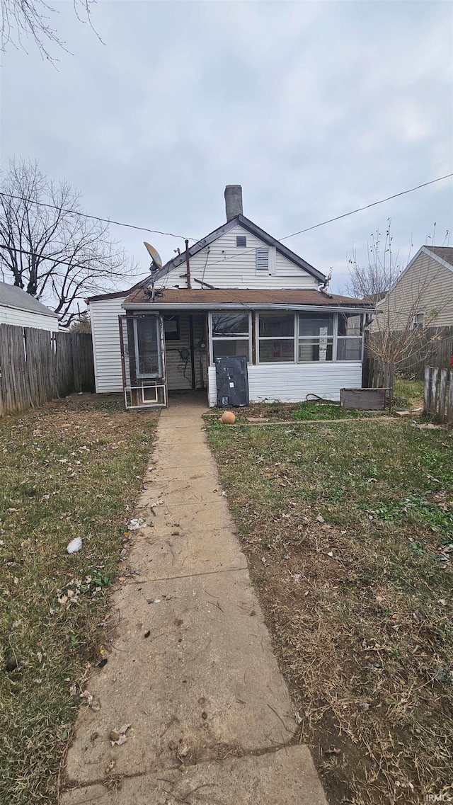 rear view of property with a lawn and a sunroom