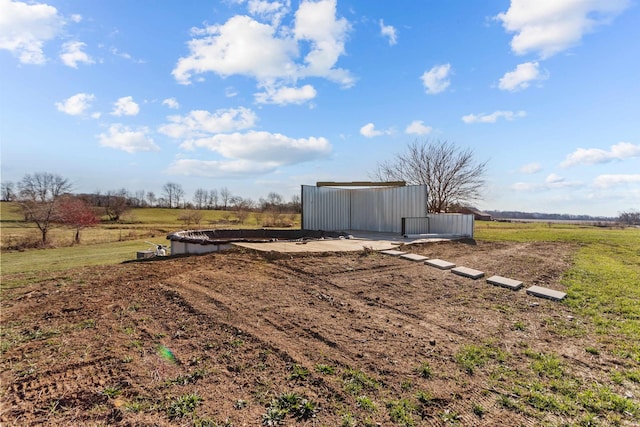 entry to storm shelter featuring a rural view and an outdoor structure