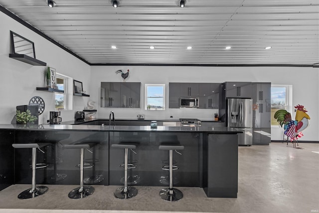 kitchen with kitchen peninsula, appliances with stainless steel finishes, ornamental molding, and a breakfast bar area