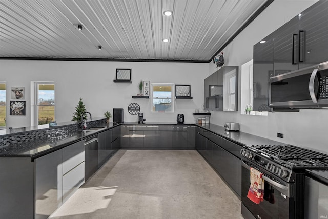 kitchen featuring kitchen peninsula, dark stone counters, stainless steel appliances, sink, and pendant lighting