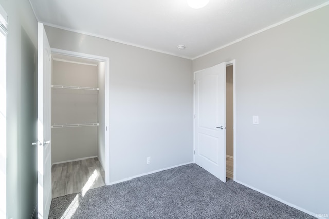 unfurnished bedroom with dark carpet, ornamental molding, and a closet