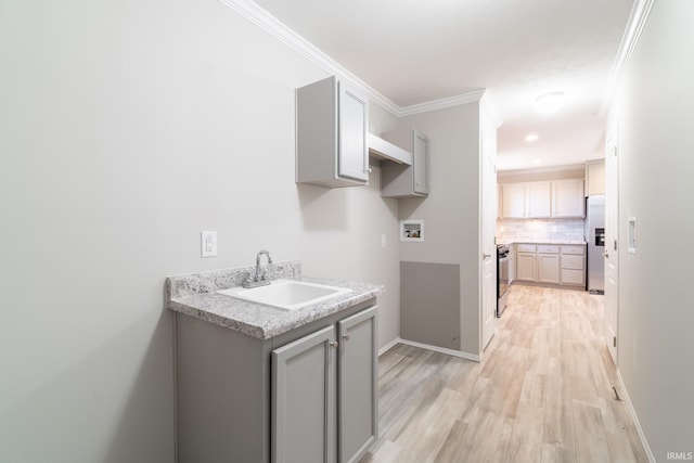 kitchen with gray cabinetry, sink, light wood-type flooring, appliances with stainless steel finishes, and ornamental molding