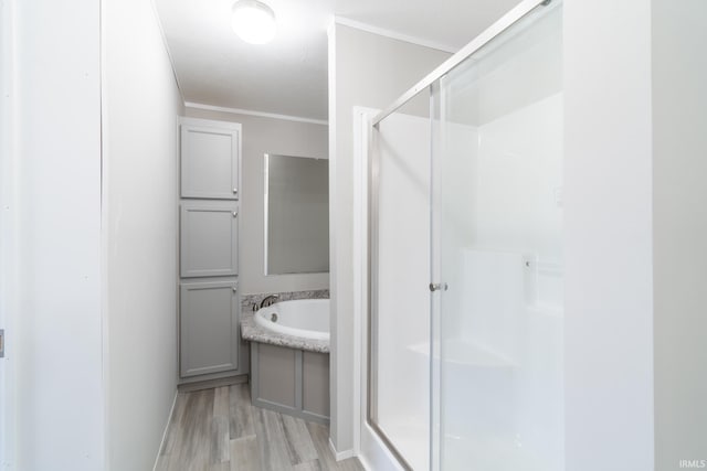 bathroom with hardwood / wood-style flooring, ornamental molding, and shower with separate bathtub