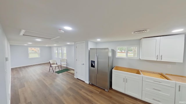 kitchen with stainless steel fridge, white cabinetry, light hardwood / wood-style flooring, and plenty of natural light