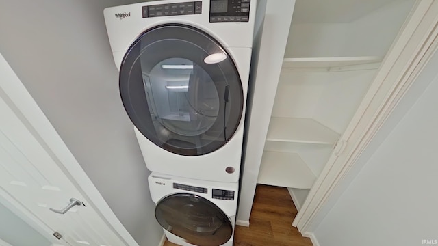 laundry room featuring dark hardwood / wood-style flooring and stacked washer / dryer