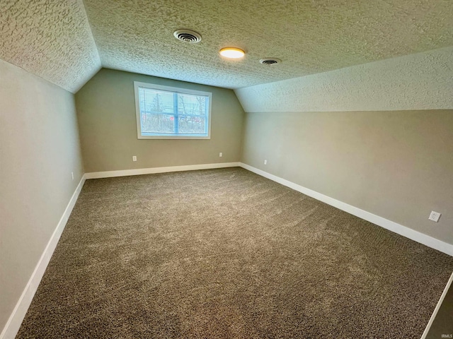 additional living space with vaulted ceiling, carpet, and a textured ceiling