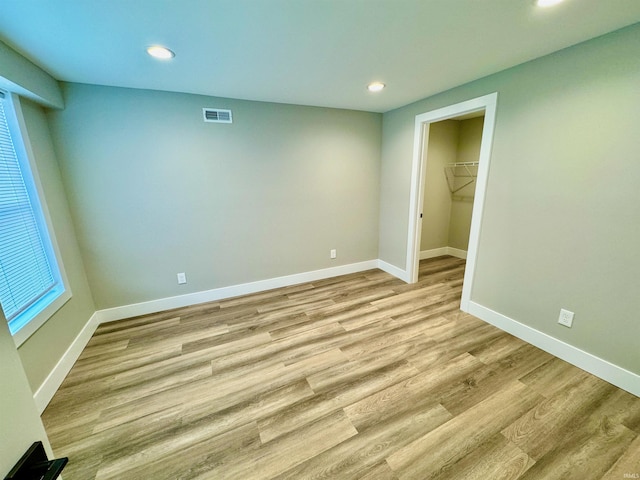 unfurnished bedroom with a closet, light hardwood / wood-style flooring, and a spacious closet