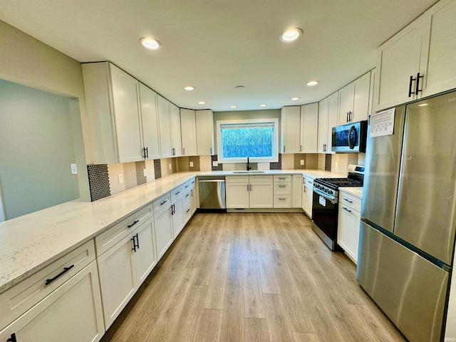 kitchen featuring sink, light stone counters, appliances with stainless steel finishes, white cabinets, and light wood-type flooring