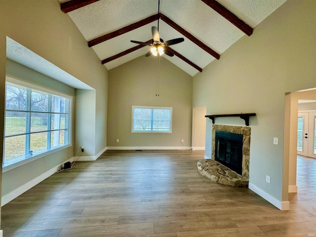 unfurnished living room with beam ceiling, ceiling fan, light hardwood / wood-style flooring, and high vaulted ceiling