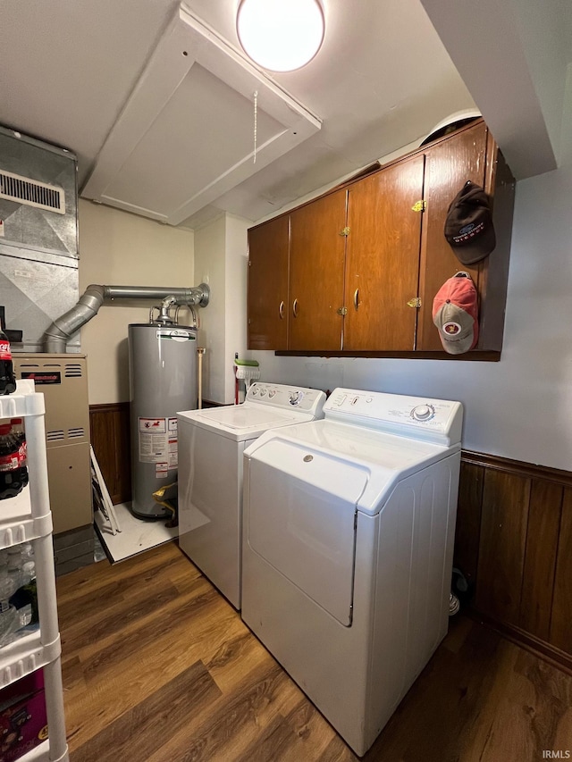 clothes washing area featuring washer and clothes dryer, cabinets, gas water heater, wooden walls, and dark hardwood / wood-style flooring