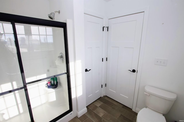 bathroom featuring hardwood / wood-style floors, a shower with shower door, and toilet