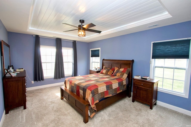 bedroom featuring ceiling fan, light carpet, and a tray ceiling