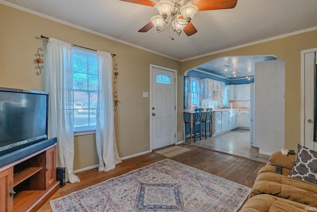 entryway with a textured ceiling, ceiling fan, light wood-type flooring, and crown molding