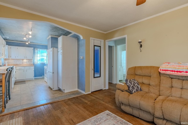 living room with a textured ceiling, light wood-type flooring, ceiling fan, and crown molding