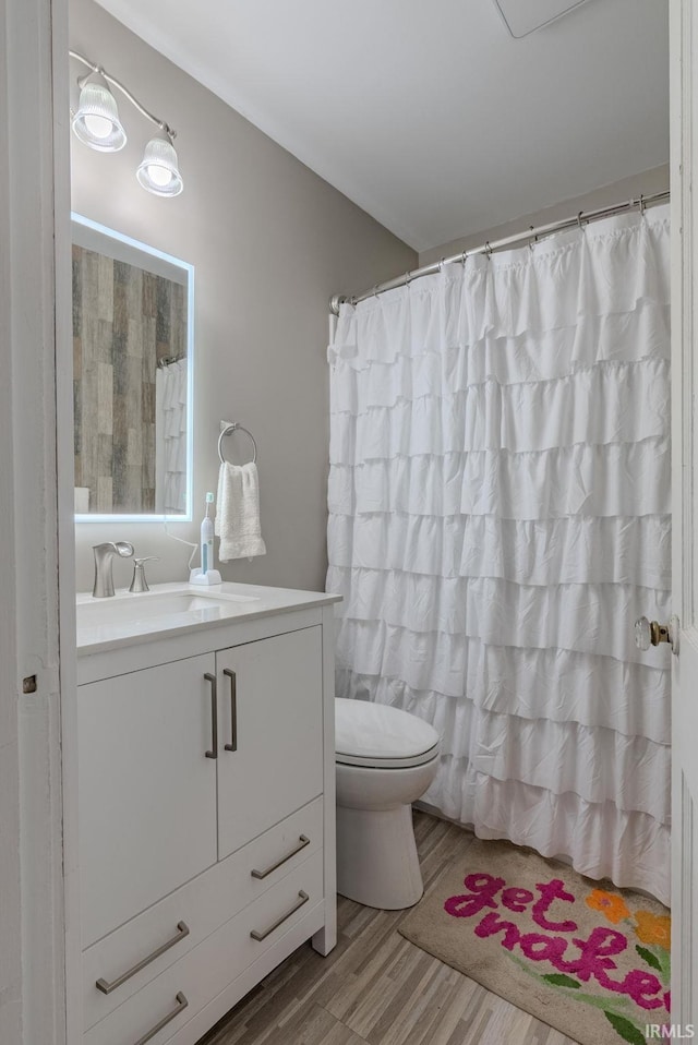 bathroom featuring vanity, toilet, wood-type flooring, and walk in shower