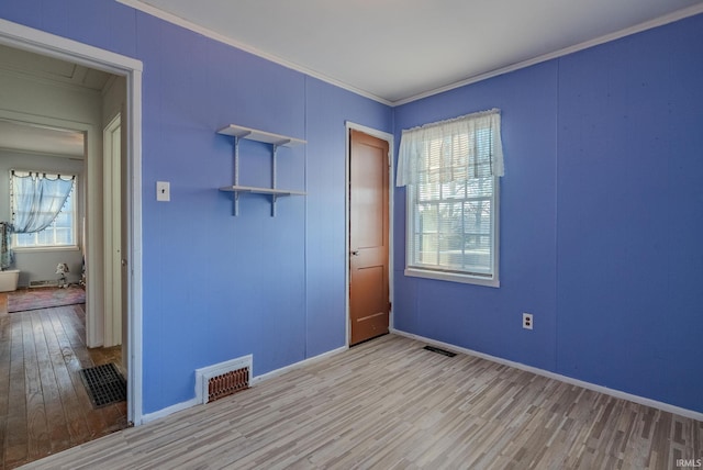 empty room with crown molding, light hardwood / wood-style flooring, and a healthy amount of sunlight