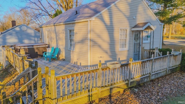 back of property featuring a wooden deck and a hot tub