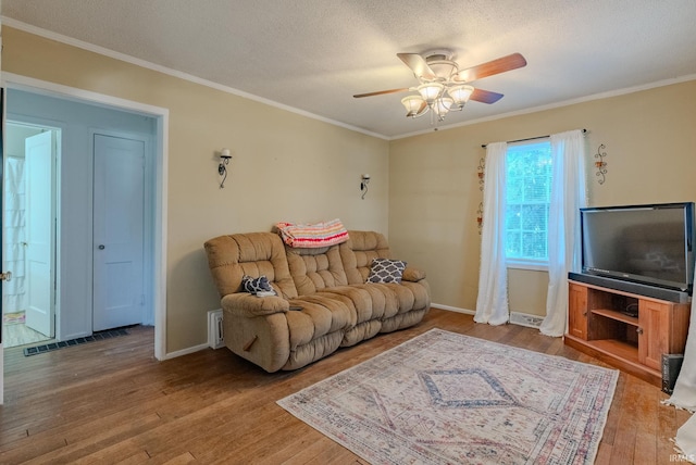 living room with ceiling fan, hardwood / wood-style floors, a textured ceiling, and ornamental molding