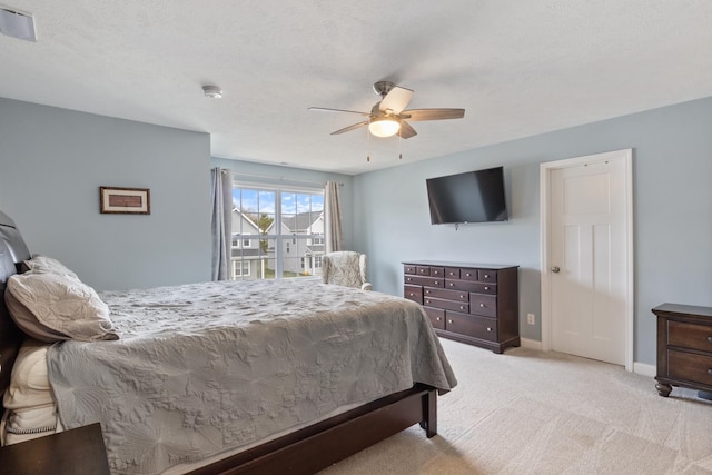 bedroom with ceiling fan, light colored carpet, and a textured ceiling