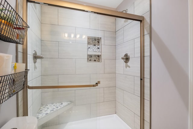 bathroom featuring a shower with door and toilet