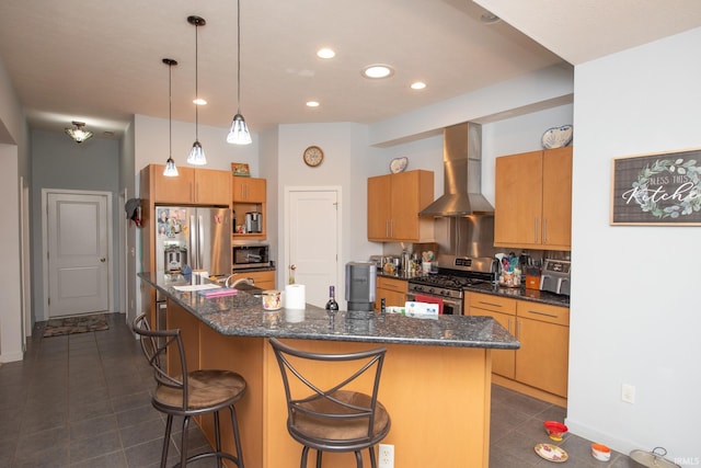 kitchen featuring appliances with stainless steel finishes, wall chimney exhaust hood, hanging light fixtures, and a center island with sink