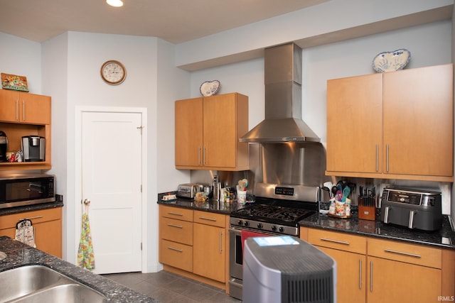 kitchen featuring dark stone countertops, dark tile patterned floors, stainless steel appliances, and wall chimney exhaust hood