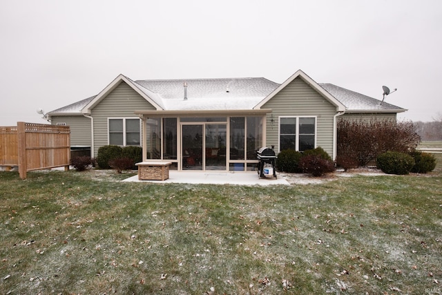 rear view of property featuring a sunroom, a patio, and a lawn